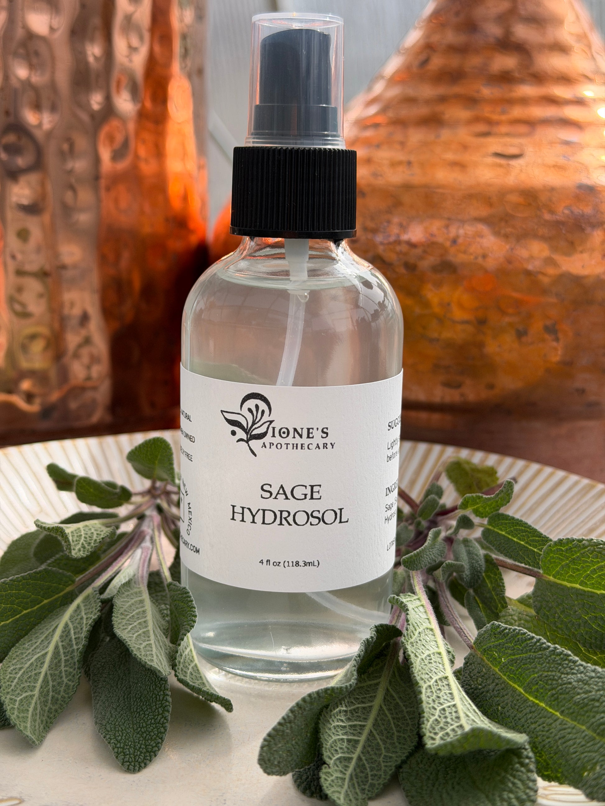 Bottle of Sage Hydrosol with a plant on a textured surface