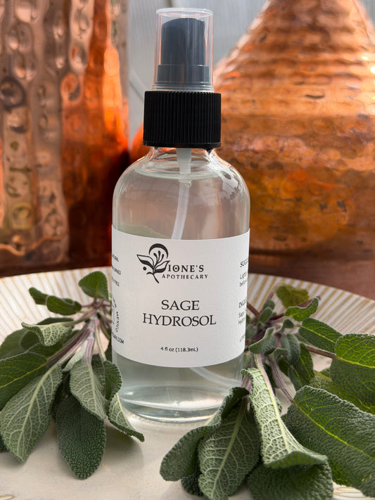 Bottle of Sage Hydrosol with a plant on a textured surface